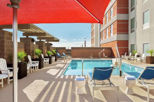 a pool on the rooftop of a hotel with chairs and an umbrella at Home2 Suites By Hilton Scottsdale Salt River in Scottsdale