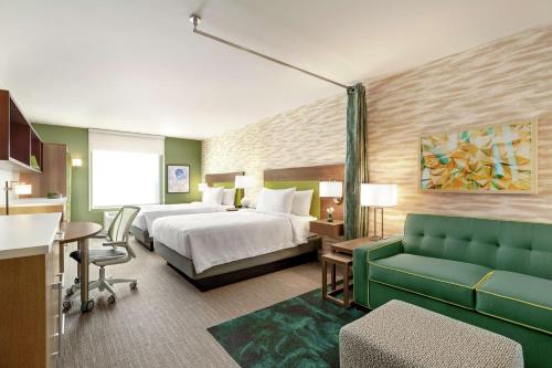 a hotel room with a bed and a green couch at Home2 Suites By Hilton Scottsdale Salt River in Scottsdale