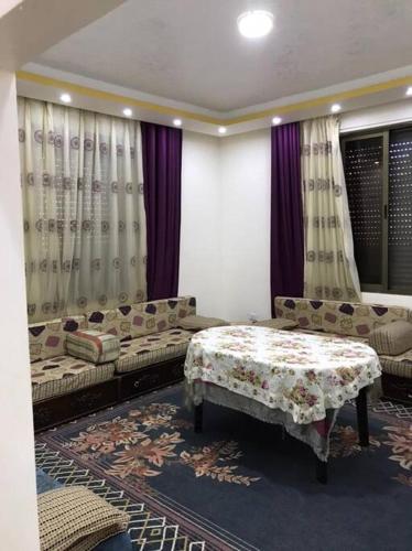 a living room with couches and a table and curtains at Your cozy apartment in Al-Karak in Kerak