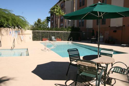 a table and chairs with an umbrella next to a pool at Hampton Inn Glendale-Peoria in Peoria