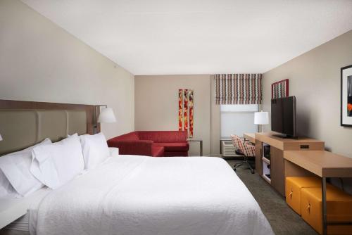 a hotel room with a large bed and a red couch at Hampton Inn Glendale-Peoria in Peoria