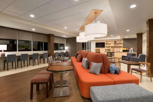 a lobby with an orange couch and a table and chairs at Home2 Suites By Hilton Glendale Westgate in Glendale