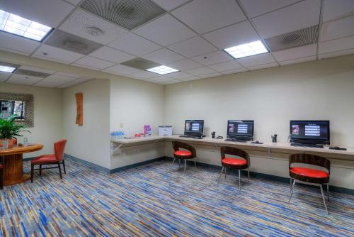 a waiting room with red chairs and a desk with two monitors at DoubleTree by Hilton Phoenix North in Phoenix