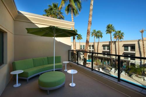 a balcony with a green couch and an umbrella at Hampton Inn & Suites Scottsdale On Shea Blvd in Scottsdale