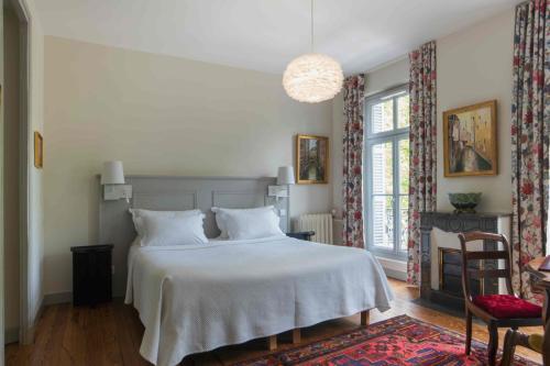 1 dormitorio con 1 cama blanca y 1 silla en B&B Le Clos d'Argenson, en Bergerac