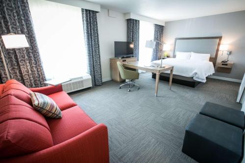 a hotel room with a bed and a red couch at Hampton Inn & Suites Tempe/Phoenix Airport, Az in Tempe