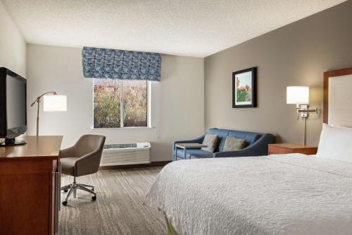 a hotel room with a bed and a desk and a couch at Hampton Inn Phoenix Midtown Downtown Area in Phoenix