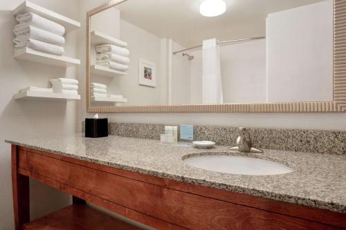 La salle de bains est pourvue d'un lavabo, d'un miroir et de serviettes. dans l'établissement Hampton Inn Phoenix Midtown Downtown Area, à Phoenix