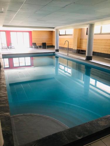 une grande piscine avec de l'eau bleue dans un immeuble dans l'établissement appartement Risoul 1850 résidence Deneb, à Risoul