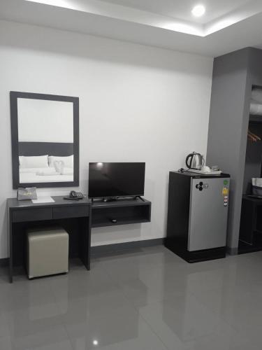 a room with a desk and a mirror and a refrigerator at D Night Suite Hotel in Bangkok