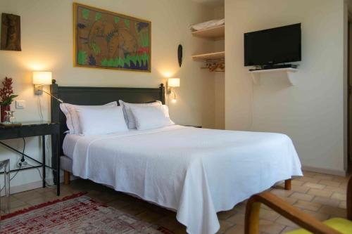a bedroom with a white bed with a tv on the wall at B&B Le Clos d'Argenson in Bergerac