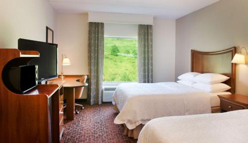 um quarto de hotel com duas camas e uma secretária e uma televisão em Hampton Inn & Suites Pittsburgh-Meadow Lands em Washington