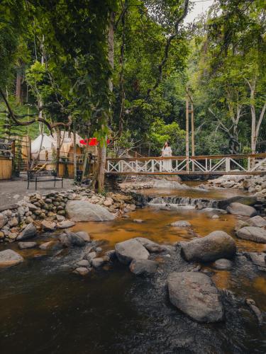 a person standing on a bridge over a river at เดอะริเวอร์ แม่กำปอง The River Maekampong Chiang Mai in Ban Pok Nai