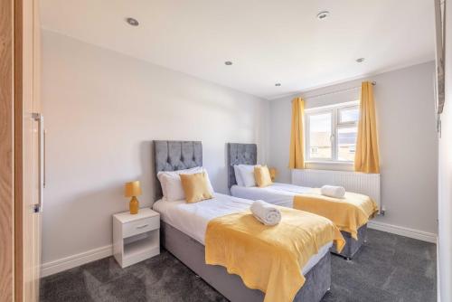 a bedroom with two beds with yellow sheets and a window at Spacious 4 Bed - Near Uxbridge/Heathrow & PARKING in Slough