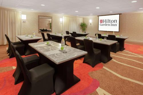 a conference room with tables and chairs and a screen at Hilton Garden Inn Pittsburgh University Place in Pittsburgh