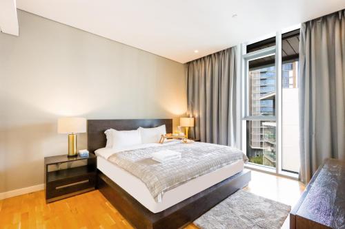 um quarto com uma cama e uma grande janela em Livbnb Suites - Elegant 1BR Suite in Bluewaters em Dubai
