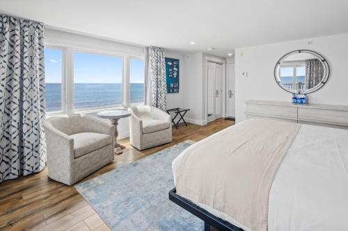 a bedroom with a bed and two chairs and a mirror at Pelham House Resort in Dennis Port