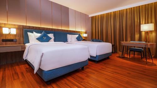 a hotel room with two beds and a desk at FUGO Hotel Samarinda in Samarinda