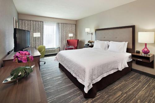 Hampton Inn & Suites Palm Desert في بالم ديزرت: غرفة فندقية بسرير وتلفزيون بشاشة مسطحة