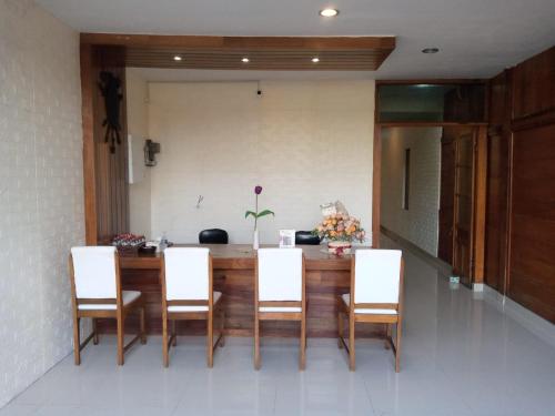 a dining room with a table and white chairs at Cahaya Losmen Sragen in Sragen