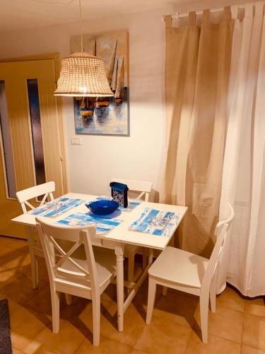 a dining room table with white chairs and a chandelier at Hiška on the cliff in Ankaran