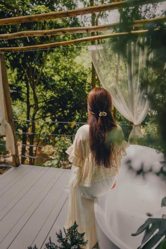 a woman in a dress standing on a deck at เดอะริเวอร์ แม่กำปอง The River Maekampong Chiang Mai in Ban Pok Nai