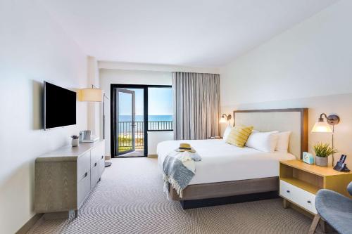 The Lodge at Gulf State Park, A Hilton Hotel في غولف شورز: غرفه فندقيه بسرير كبير وبلكونه