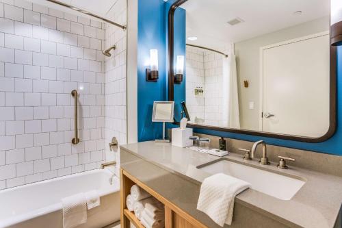 uma casa de banho com um lavatório, uma banheira e um espelho. em The Lodge at Gulf State Park, A Hilton Hotel em Gulf Shores