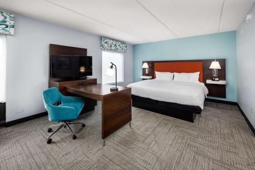 Habitación de hotel con cama, escritorio y TV. en Hampton Inn & Suites Navarre, en Navarre