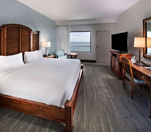 a hotel room with a bed and a desk and a television at The Island House Hotel a Doubletree by Hilton in Orange Beach
