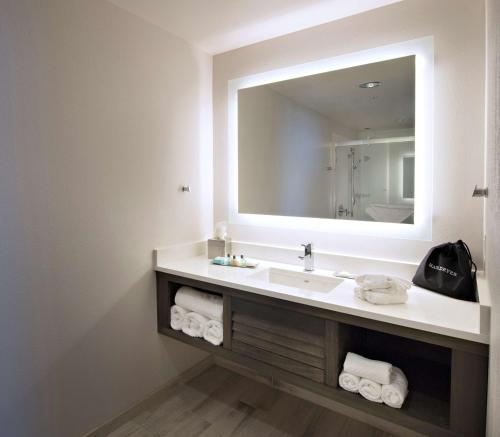 a bathroom with a sink and a large mirror at The Island House Hotel a Doubletree by Hilton in Orange Beach