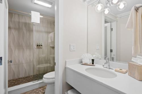 a white bathroom with a sink and a toilet at Pelham House Resort in Dennis Port