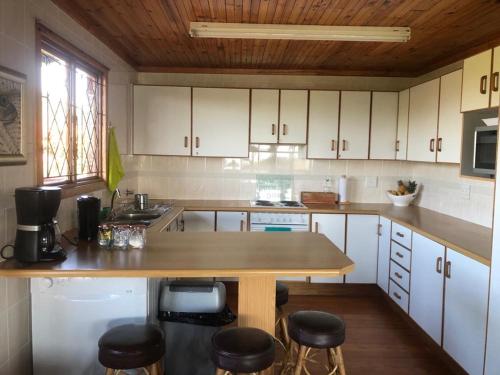 a kitchen with white cabinets and a wooden counter top at Log Cabin By The Beach in Port Edward