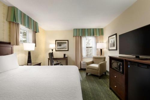 a hotel room with a bed and a flat screen tv at Hampton Inn Dover in Dover