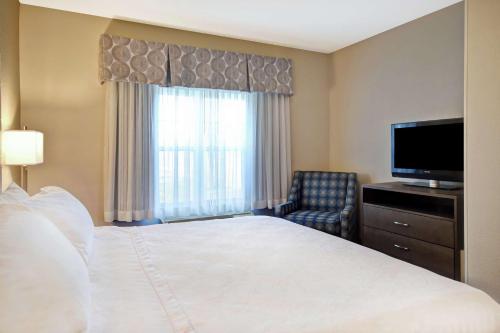 a hotel room with a bed and a flat screen tv at Homewood Suites by Hilton Dover in Dover