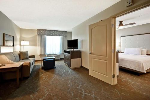 a hotel room with a bed and a couch and a television at Homewood Suites by Hilton Dover in Dover