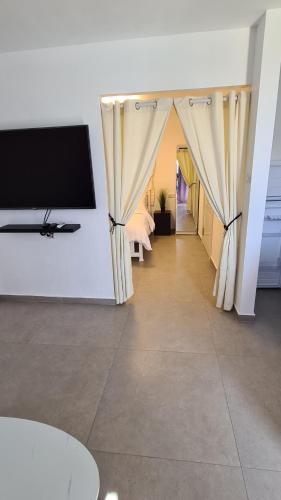 a living room with a tv and curtains at בוילה היפה של יהודית in Eilat