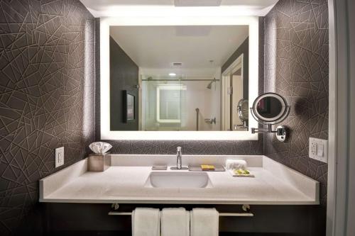 La salle de bains est pourvue d'un lavabo et d'un grand miroir. dans l'établissement DoubleTree by Hilton Deadwood at Cadillac Jack's, à Deadwood