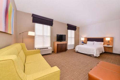 Hampton Inn & Suites by Hilton Plymouth في بليموث: غرفه فندقيه بسرير واريكه
