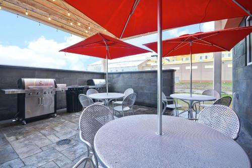 a patio with tables and chairs with red umbrellas at Home2 Suites By Hilton Rapid City in Rapid City