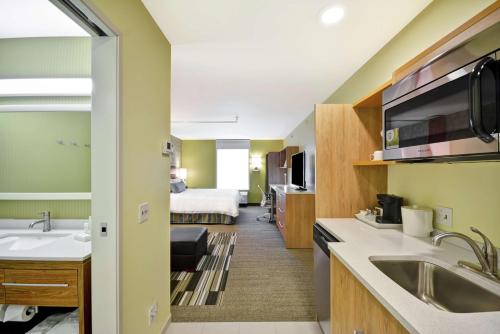 um quarto de hotel com um lavatório e uma cama em Home2 Suites By Hilton Rapid City em Rapid City