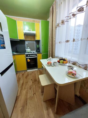 eine Küche mit gelben und grünen Schränken und einem Tisch in der Unterkunft Комфортная квартира с удобным расположением in Līsakovsk