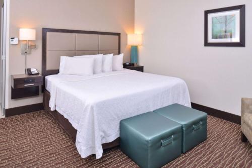 a hotel room with a large bed with a blue stool at Hampton Inn & Suites Bend in Bend