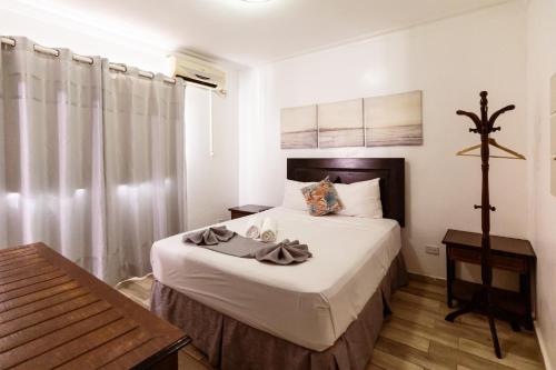 a bedroom with a bed with white sheets and a window at Hotel Las Rosas de Punta Cana in Punta Cana