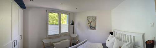 a white bedroom with a bed and a window at Ferienhaus Hellaberg in Langenbach