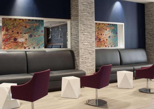 a waiting room with benches and paintings on the wall at Embassy Suites by Hilton Raleigh Crabtree in Raleigh
