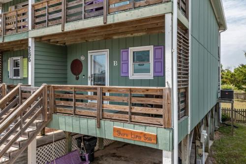 a house with a wrap around porch with a deck at That's What Sea Said home in Holden Beach