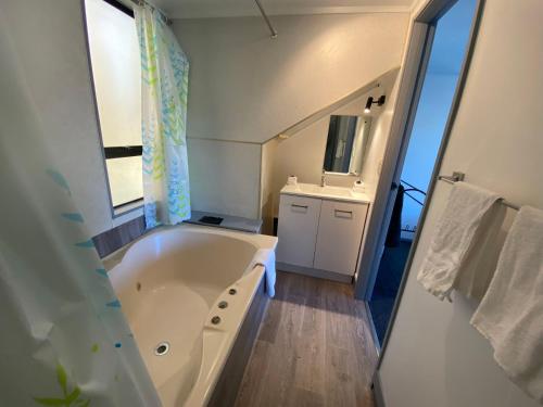 baño con bañera grande y lavamanos en Ace Motor Lodge, en Rotorua
