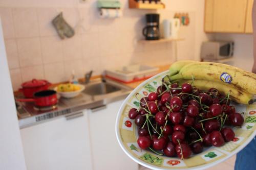 - un bol de cerises et une banane sur une assiette dans la cuisine dans l'établissement Apartments Toni, à Trogir