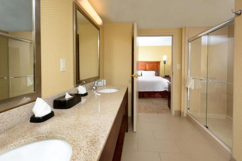 a bathroom with two sinks and a shower and a bed at Hampton Inn Raleigh Capital Blvd North in Raleigh